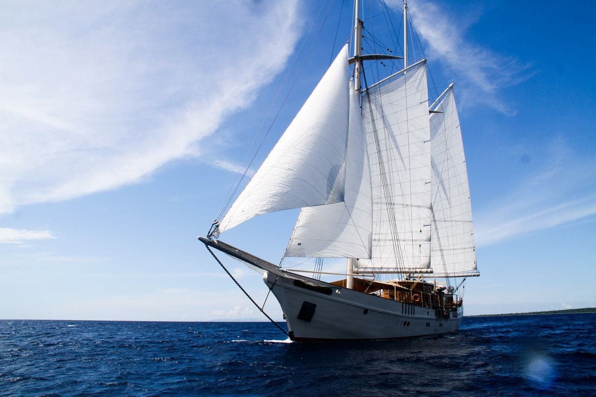 Mutiara Laut sailing in side profile under full sail against a bright blue sky