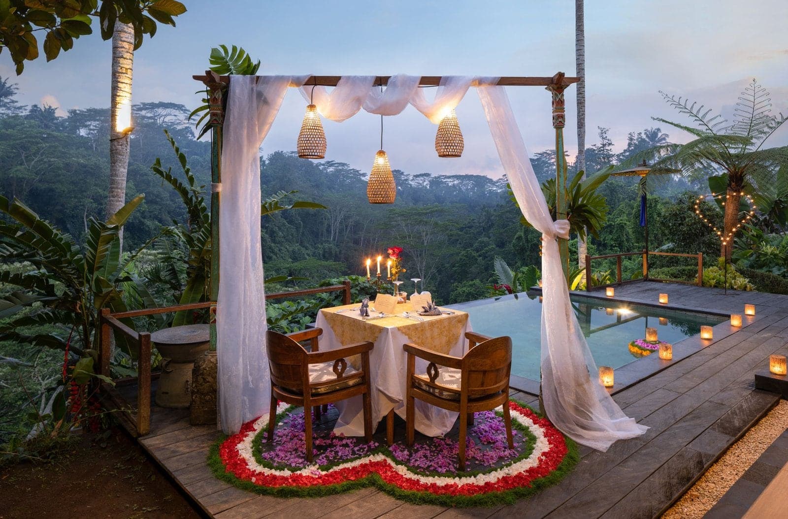 Candlelit dinner set on a deck beside the pool at Ubud Valley Resort, above the forested valley at dusk