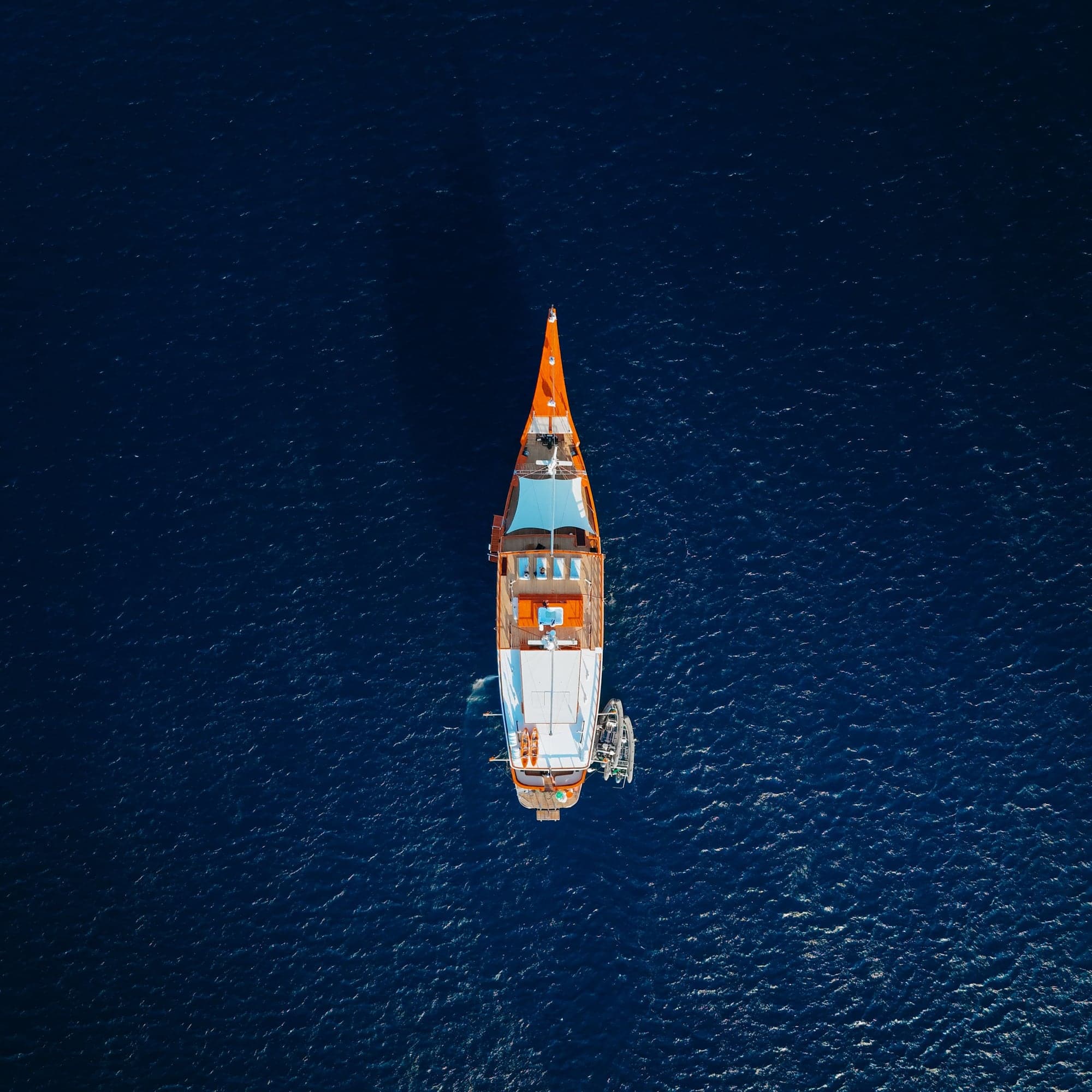 Aerial view looking down on the Sanctuary phinisi under way in deep blue water